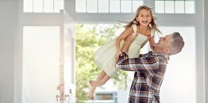 Shot of a father picking up his daughter as he enters his house